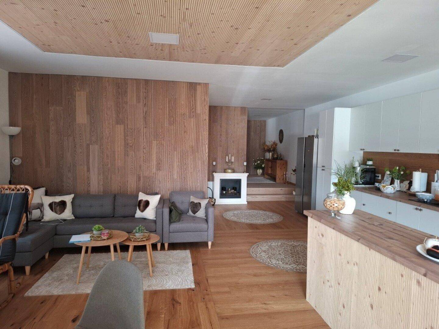 Offener Wohnbereich mit Holzwänden, Kamin und integrierter Küche.