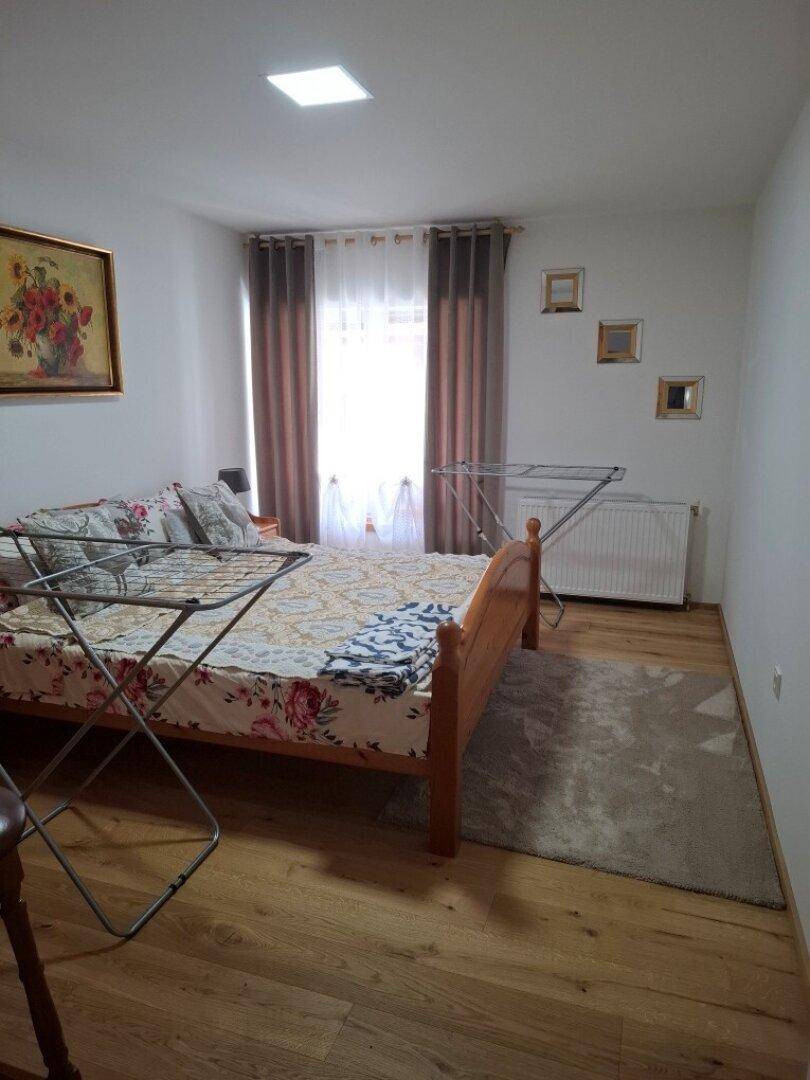 Schlafzimmer mit Holzbett, Parkettboden und Fenster mit Vorhängen.