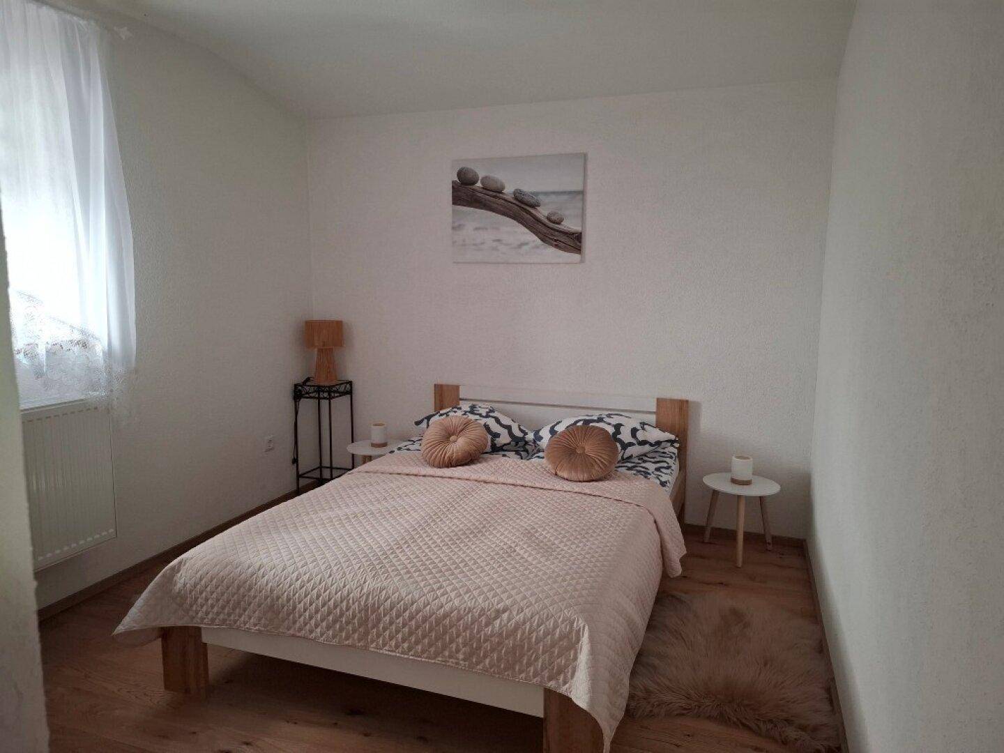 Helles Schlafzimmer mit Doppelbett, Parkettboden und schlichtem Dekor.