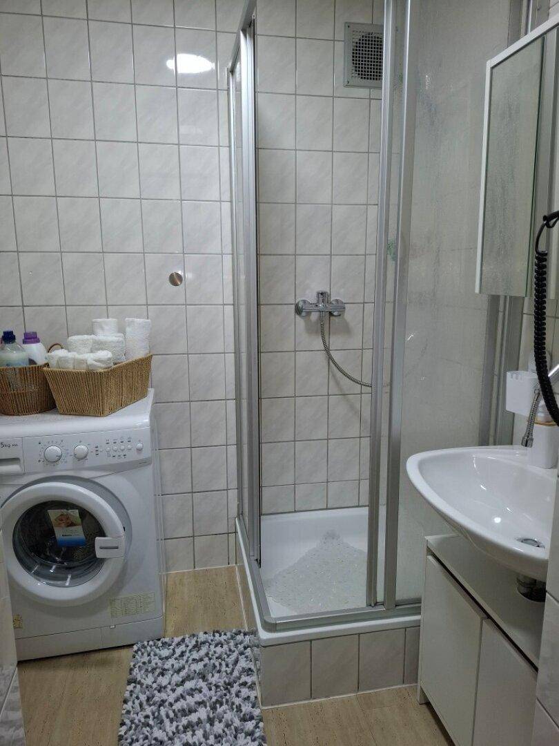 Badezimmer mit Duschkabine, Waschbecken und Fliesen an den Wänden.