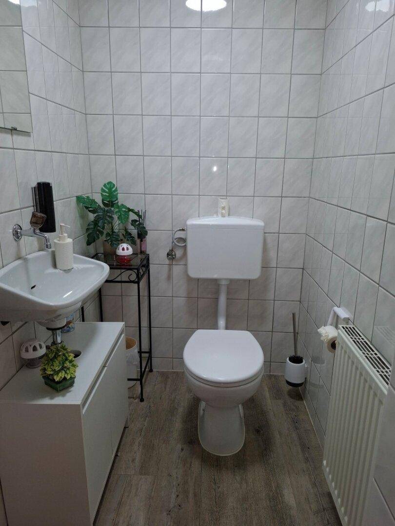 Kleines Badezimmer mit WC, Waschbecken und hellen Fliesen.