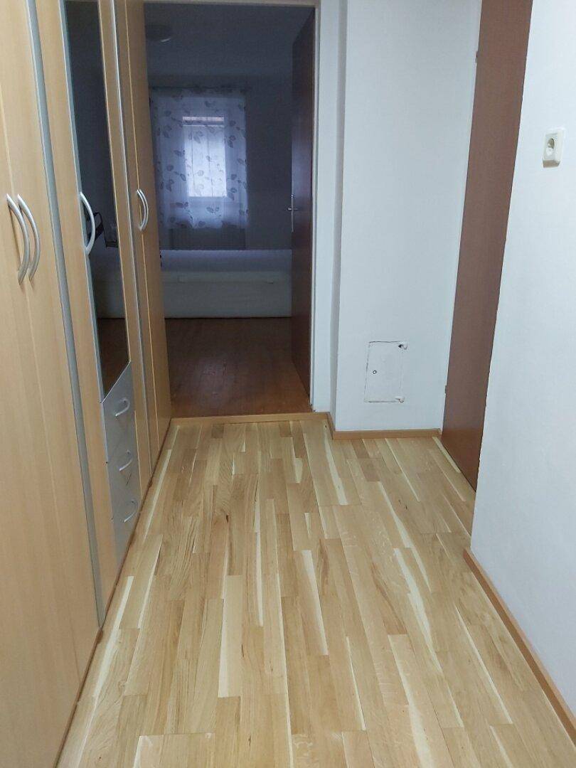 Heller Flur mit Parkettboden und integrierten Schränken.