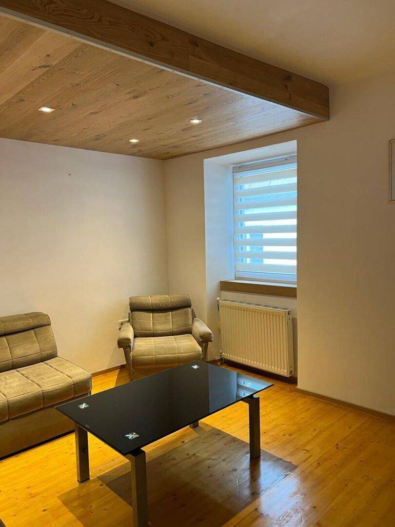 Wohnzimmer mit Holzbalkendecke, bequemen Sesseln und Couchtisch.
