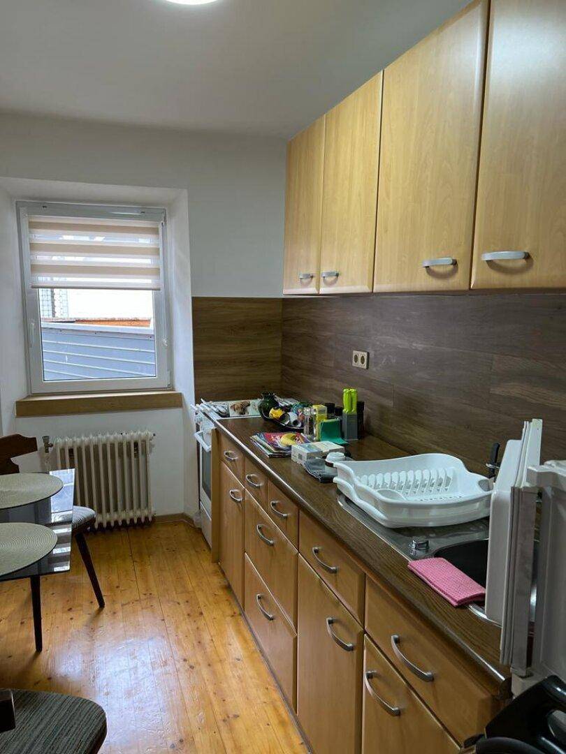 Küche mit Holzschränken, Fenster und Essbereich.