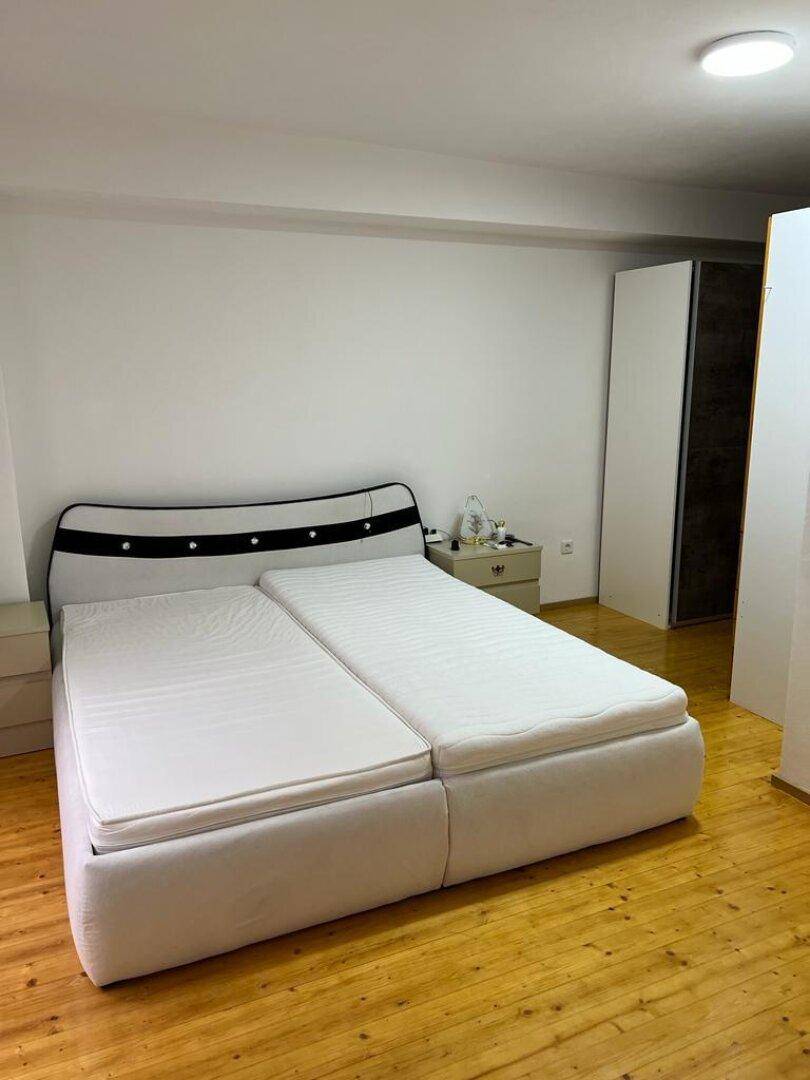 Schlafzimmer mit Doppelbett, Parkettboden und weißem Kleiderschrank.