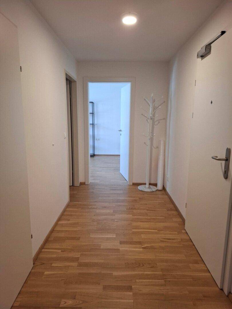 Heller Flur mit Holzfußboden und Garderobe, der zu den verschiedenen Räumen führt.