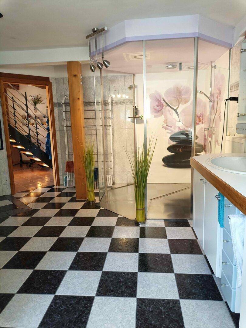 Modernes Badezimmer mit schwarz-weißem Schachbrettmuster-Fliesenboden und Glasdusche.