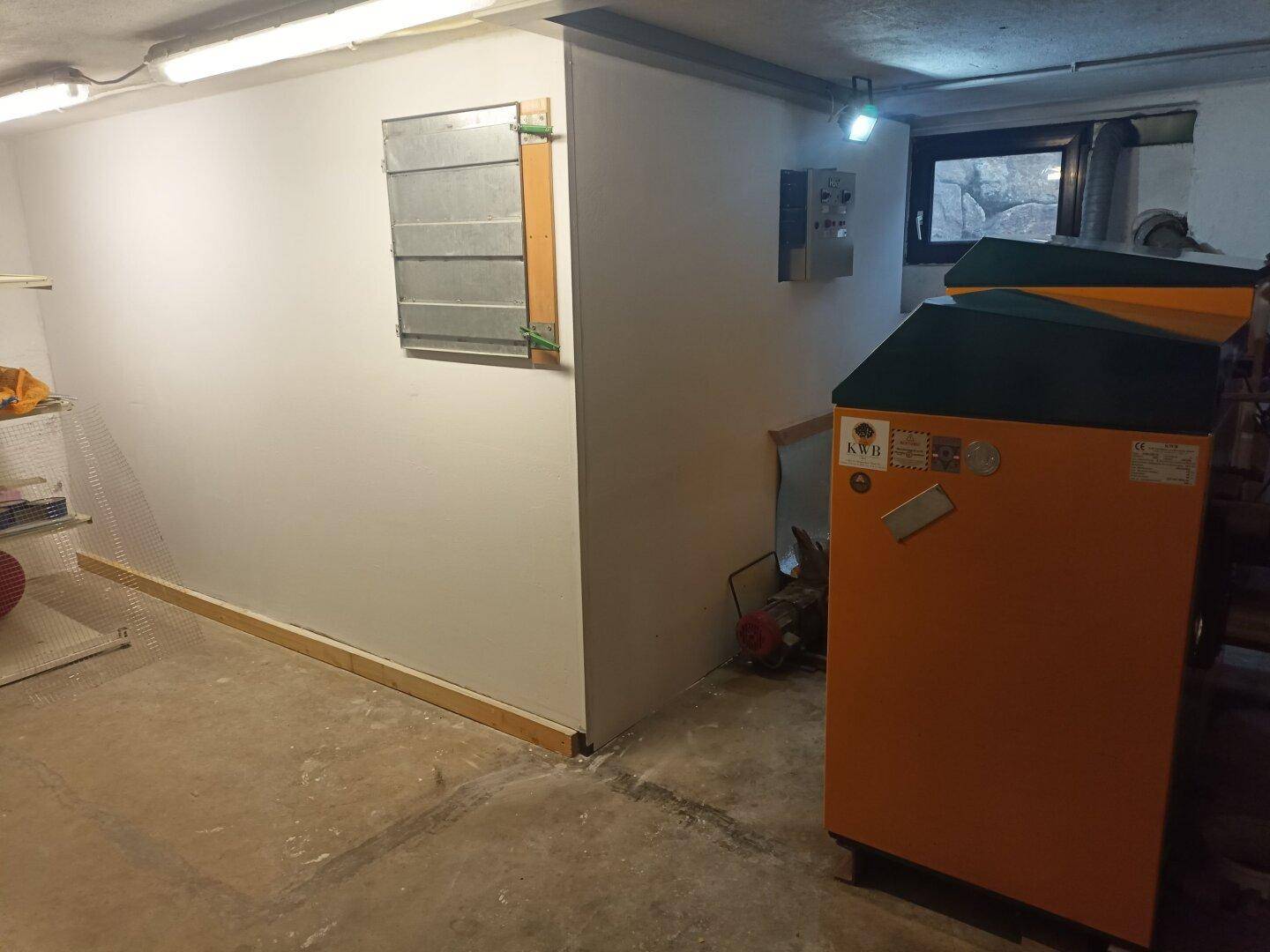 Heller Kellerraum mit Heizungsanlage und kleinem Fenster, ideal als Technik- oder Abstellraum.