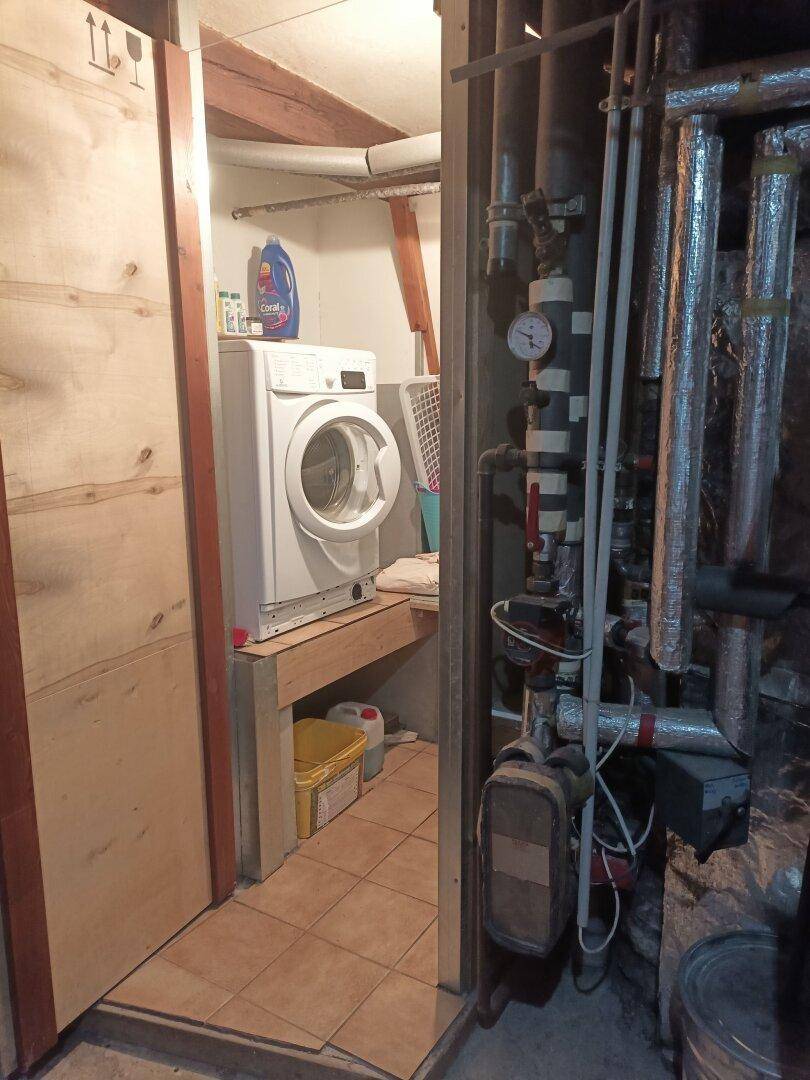 Praktischer Waschraum im Keller mit Waschmaschine und funktionalen Installationen.