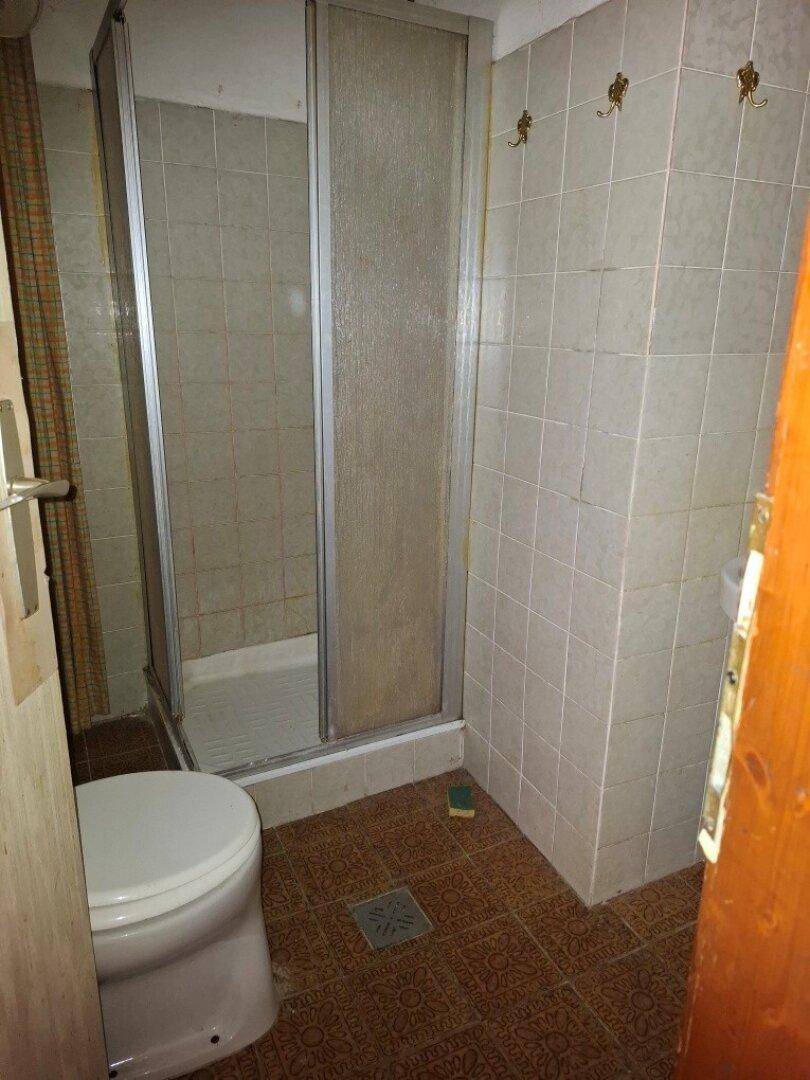 Badezimmer mit Duschkabine, WC und gefliesten Wänden in einfacher Ausführung.