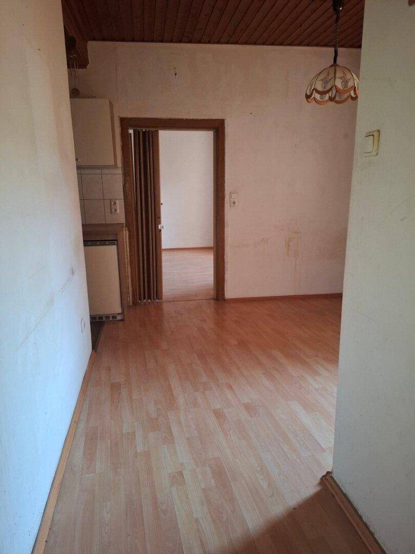Flur mit Laminatboden und Blick in einen weiteren Raum sowie einen Teil der Küchenzeile.