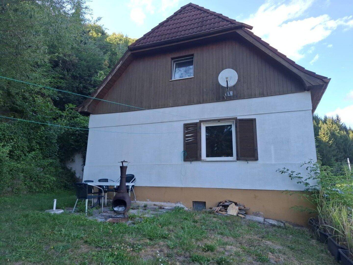 Rückansicht des Hauses mit kleinem Gartenbereich, Sitzgelegenheiten und Feuerstelle.