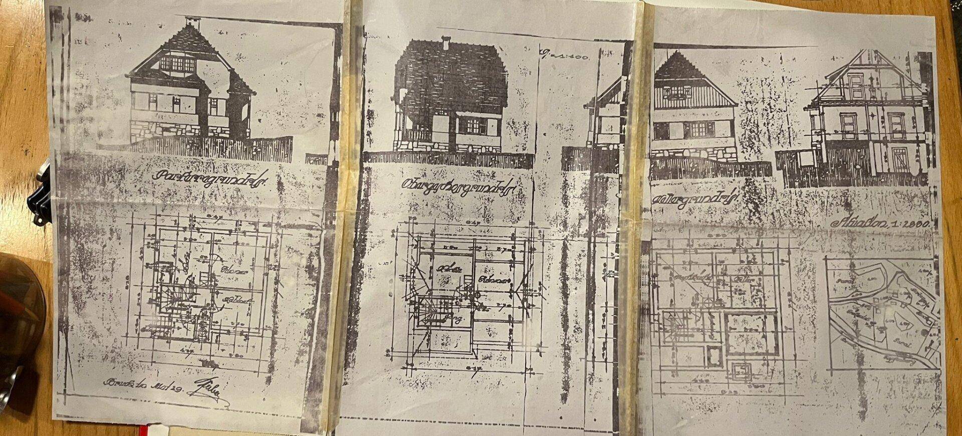 Historische Baupläne und Grundrisse des Gebäudes auf vergilbtem Papier.