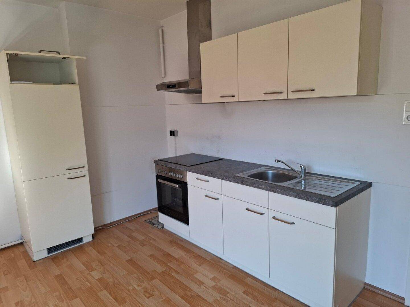 Detailansicht der modernen Küchenzeile mit Spüle, Kochfeld, Backofen und Dunstabzugshaube.