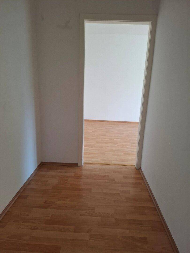 Heller Flur mit Laminatboden, der zu einem weiteren Raum der Wohnung führt.