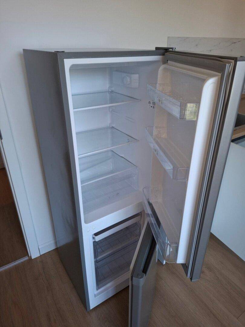 Nahaufnahme eines sauberen, leeren Kühlschranks mit geöffneter Tür und mehreren Ablagefächern.