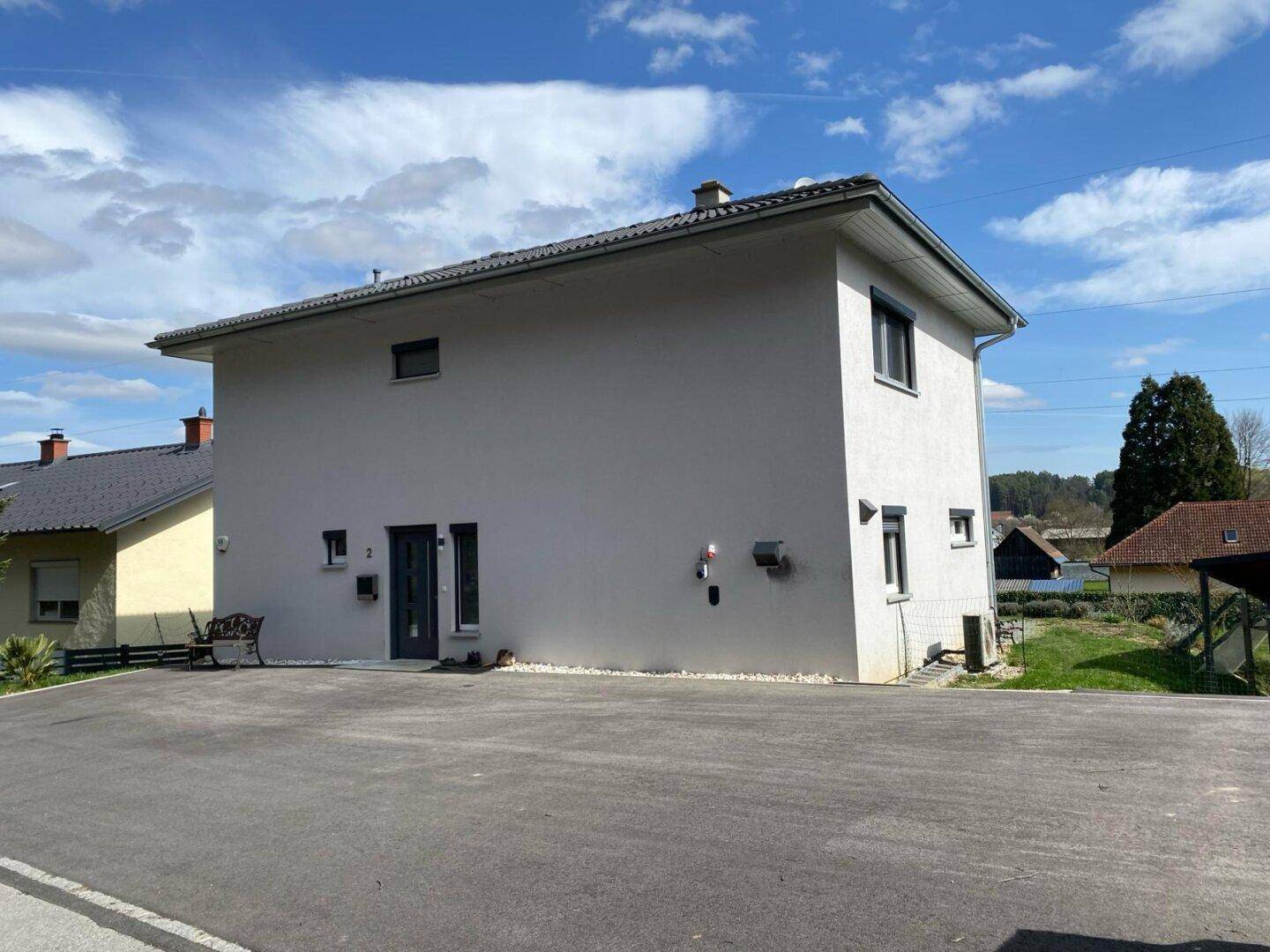 Seitenansicht des modernen Hauses mit grauer Fassade und Blick auf die umliegende ländliche Gegend.