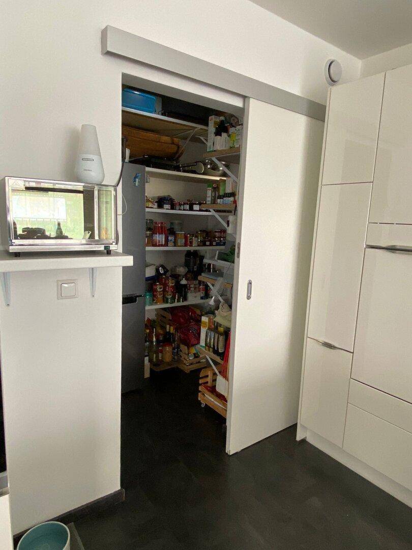 Praktische Speisekammer mit vielen Regalen und Vorräten, direkt angrenzend an die moderne Küche.