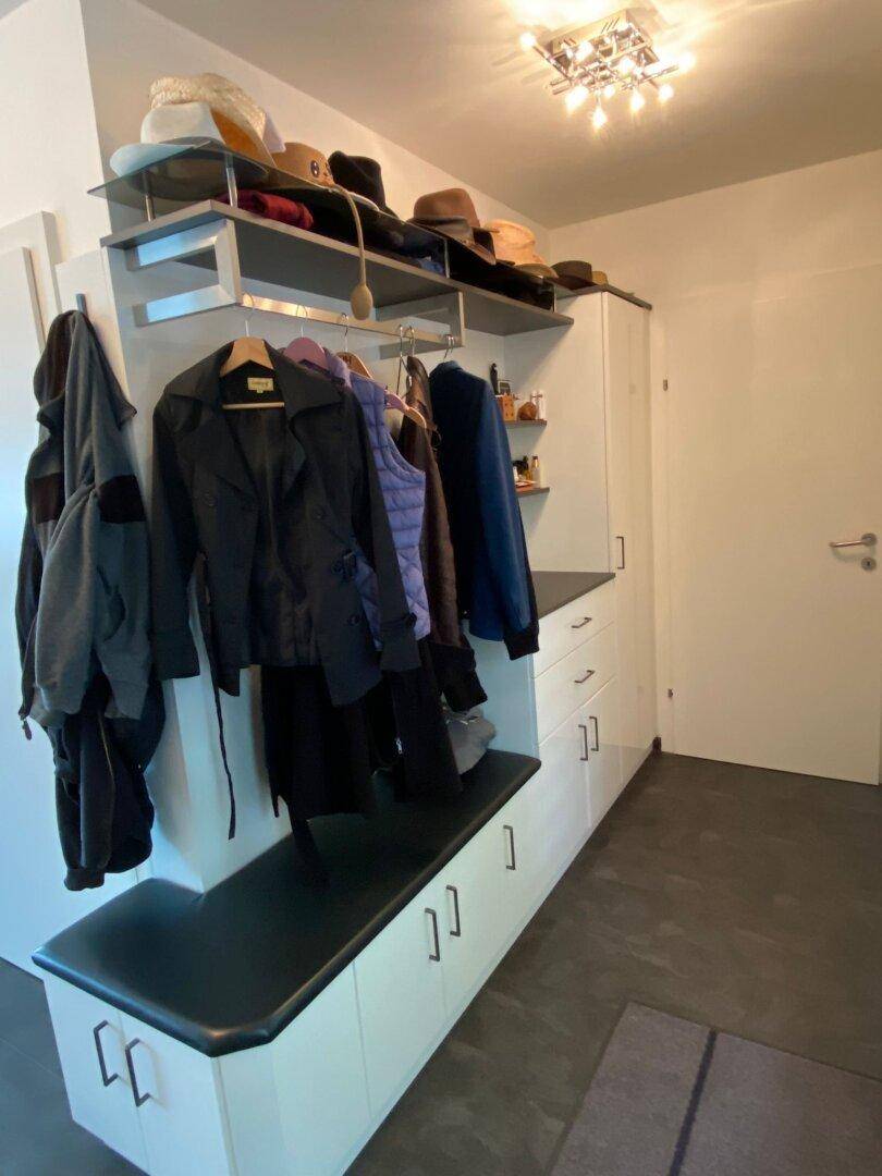Heller Flur mit praktischer Garderobe, integrierter Sitzbank und viel Stauraum für Kleidung.