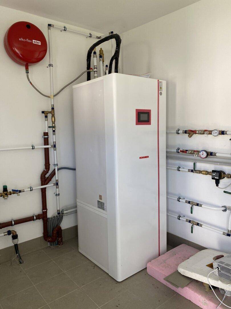 Technikraum mit moderner Heizungsanlage, sichtbaren Rohren und Fliesenboden.