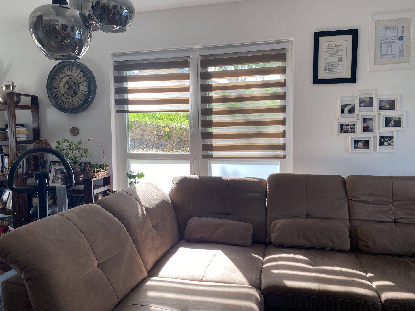 Heller Wohnbereich mit bequemer Couch und großen Fenstern, die viel Licht hereinlassen.