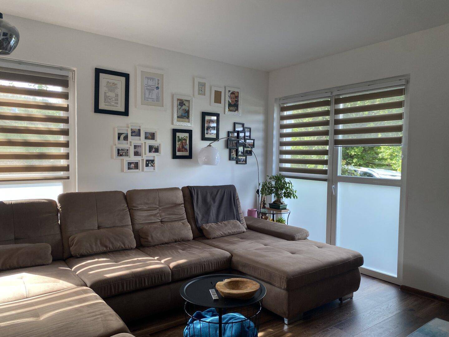 Geräumiges Wohnzimmer mit großem Ecksofa, vielen Bildern und Zugang zum Außenbereich.