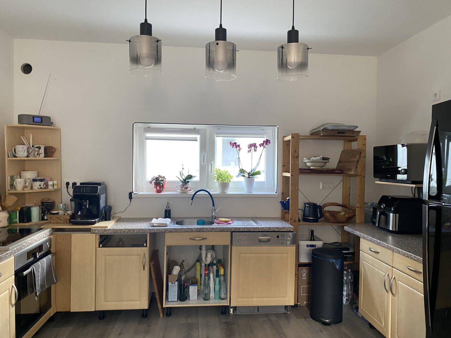 Funktionale Küche mit hellen Holzschränken, Spülbecken und Fenster mit Tageslicht.