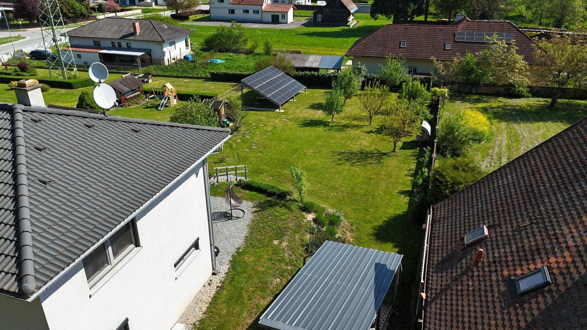 Luftaufnahme der Wohngegend mit Einfamilienhäusern, grünen Gärten und einer Photovoltaikanlage.