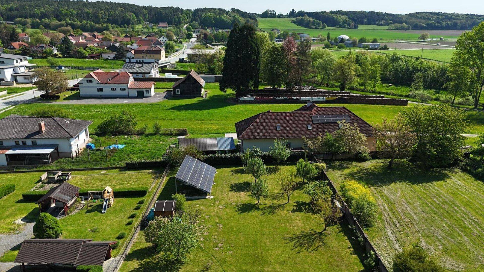 Panoramablick aus der Luft auf die ländliche Umgebung mit weiten Feldern und einem Haus mit Solaranlage.