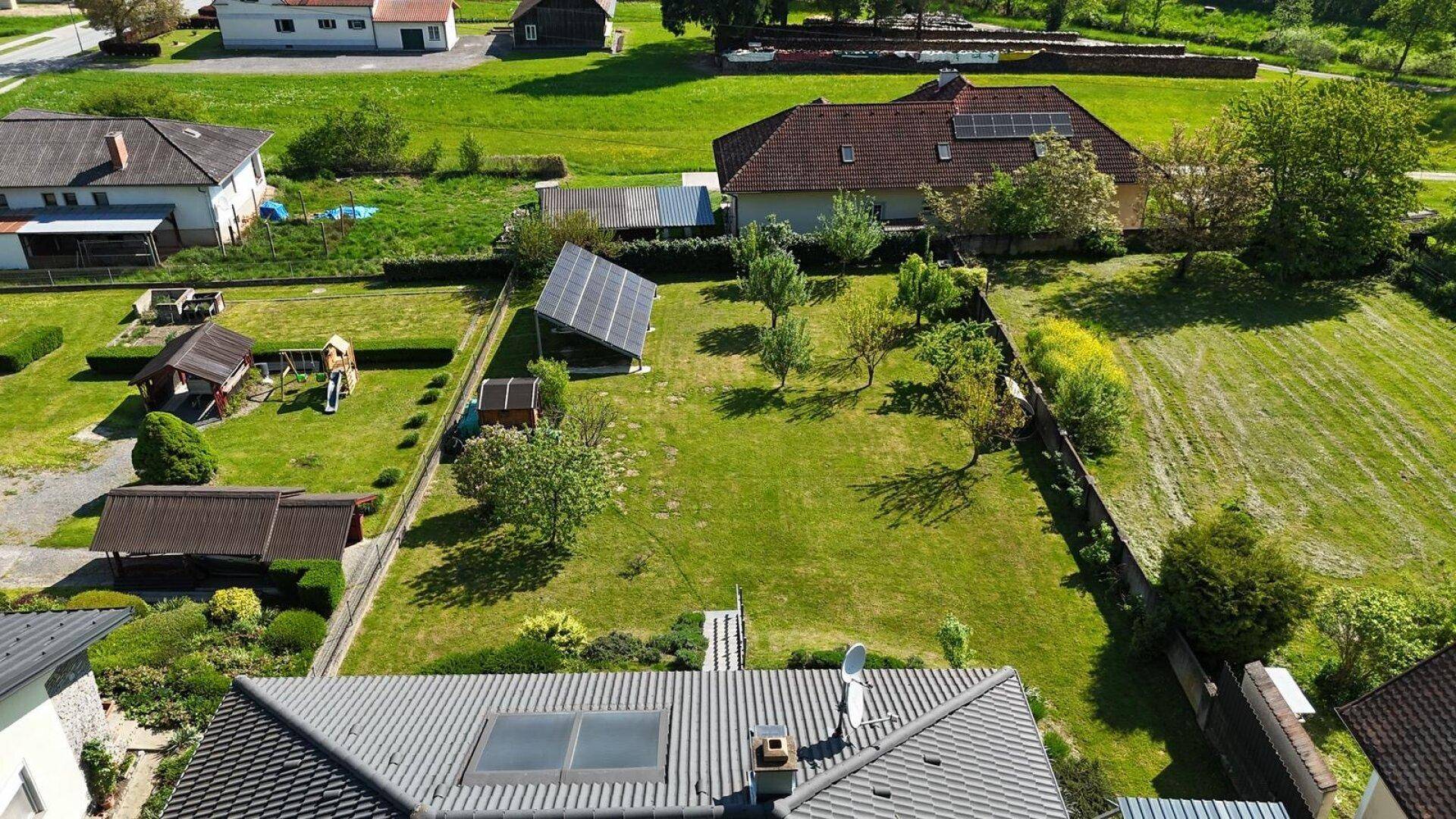 Luftaufnahme der Wohnsiedlung mit grünen Gärten, Feldern und dem Dach des modernen Einfamilienhauses.