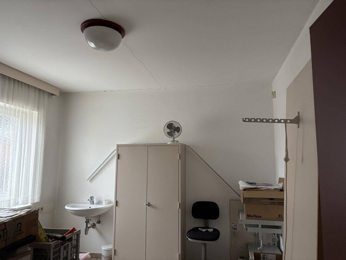 Kleiner Abstellraum oder Nebenraum mit Waschbecken, Schrank und Fenster.