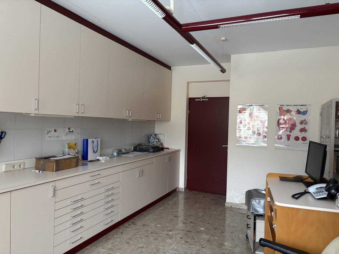 Langer Schrankbereich in einem Büro oder Sprechzimmer mit viel Stauraum und gefliestem Boden.