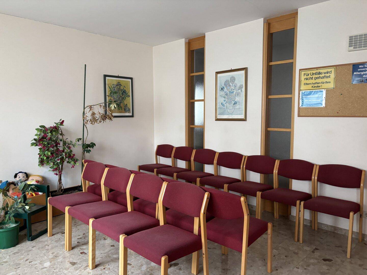 Geräumiges Wartezimmer mit vielen Sitzgelegenheiten und hohen Fenstern für ausreichend Tageslicht.