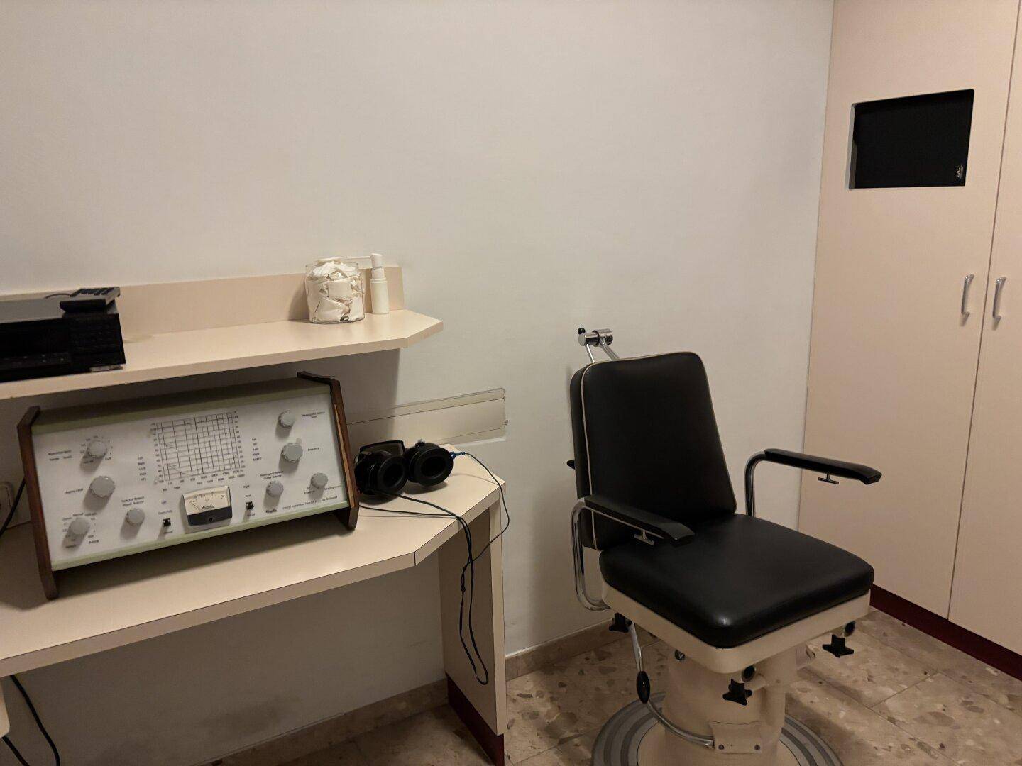 Behandlungszimmer mit speziellen medizinischen Geräten, einem Untersuchungsstuhl und Schränken.