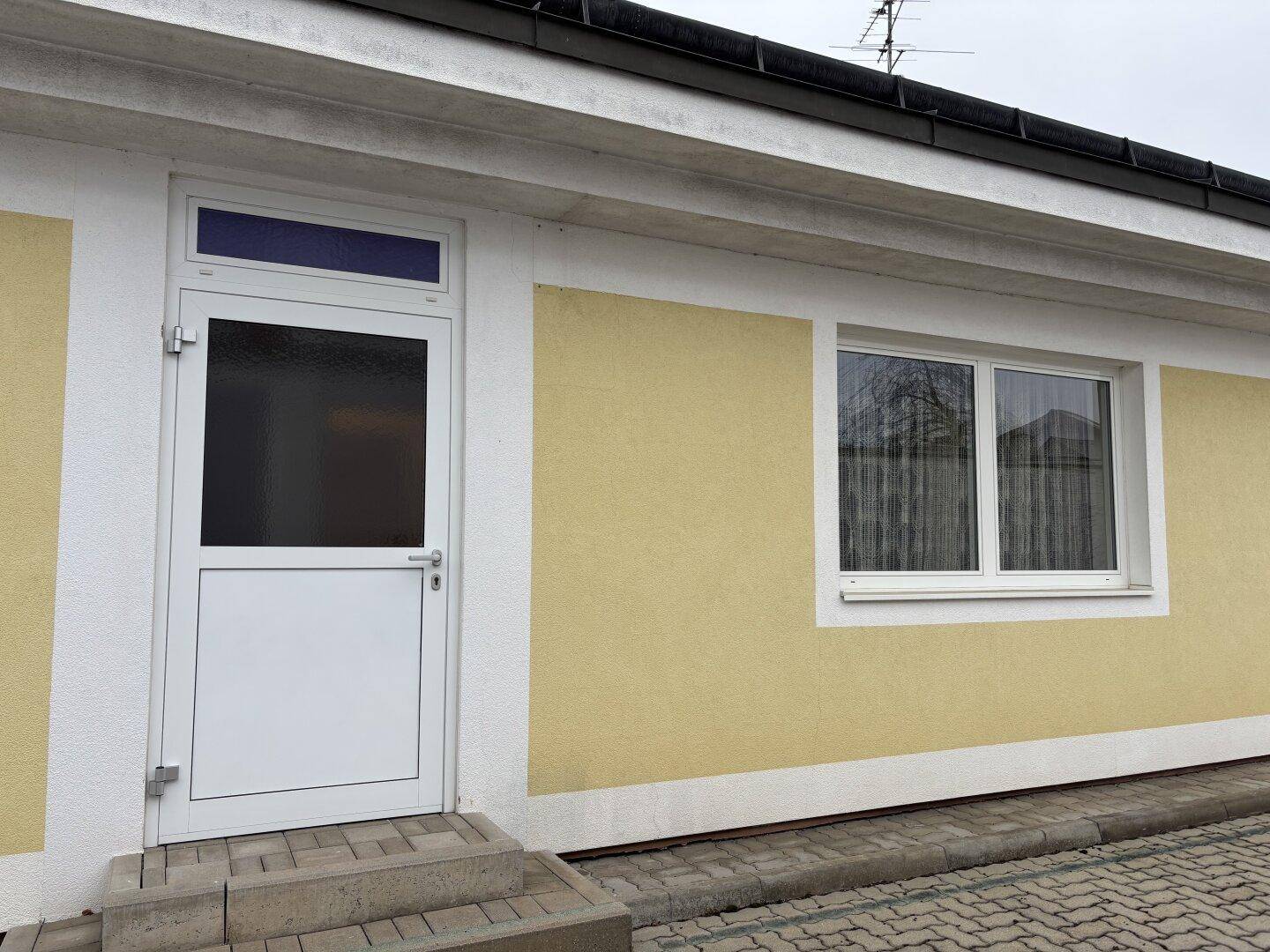 Eingangstür und Fenster an der gelben Fassade des Gebäudes.
