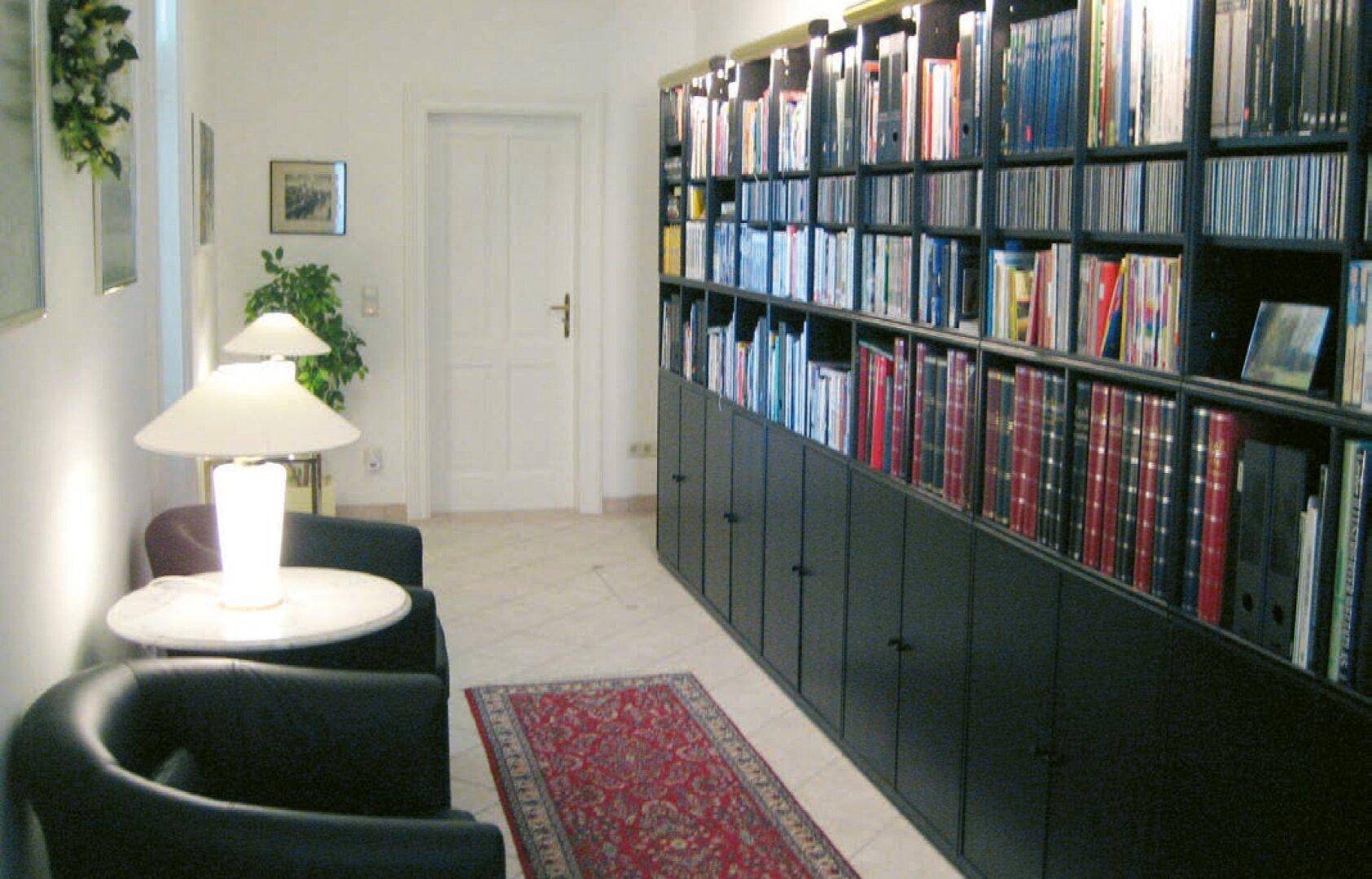 Gemütliche Bibliothek mit raumhohen Bücherregalen und bequemen Ledersesseln.