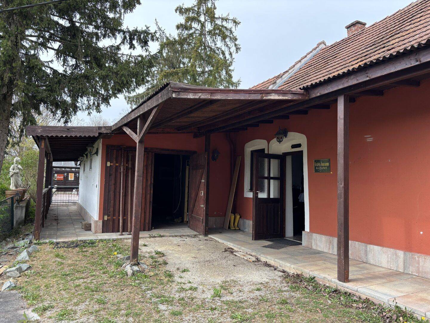 Überdachter Eingangsbereich und Seitenansicht des Hauses mit Zugang zum Garten.