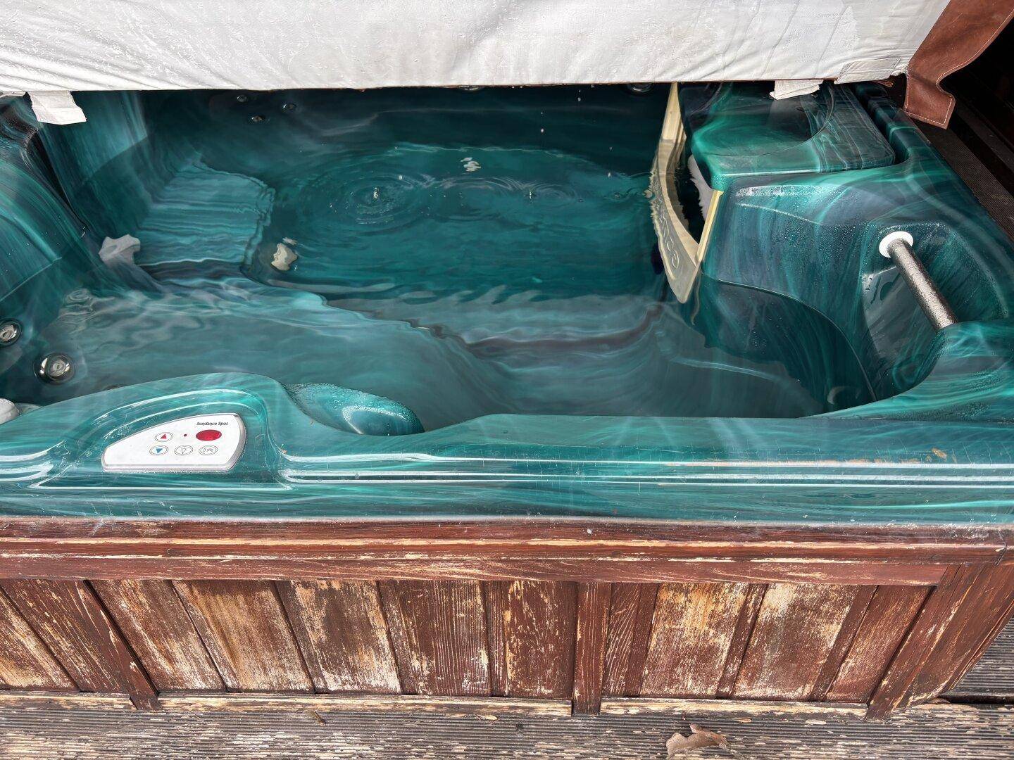 Nahaufnahme des Whirlpools mit grünlichem Wasser und Holzverkleidung.