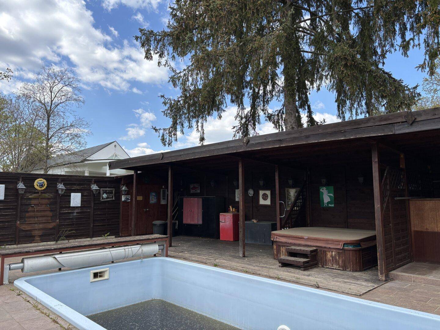 Außenbereich mit Pool und überdachtem Bereich, der einen Whirlpool und eine Bar beherbergt.