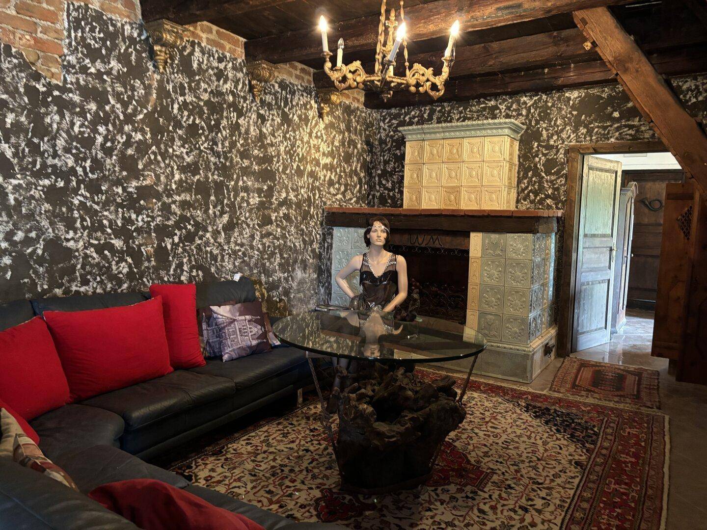 Gemütlicher Wohnbereich mit Ledersofa, Kachelofen und einem opulenten Kronleuchter.