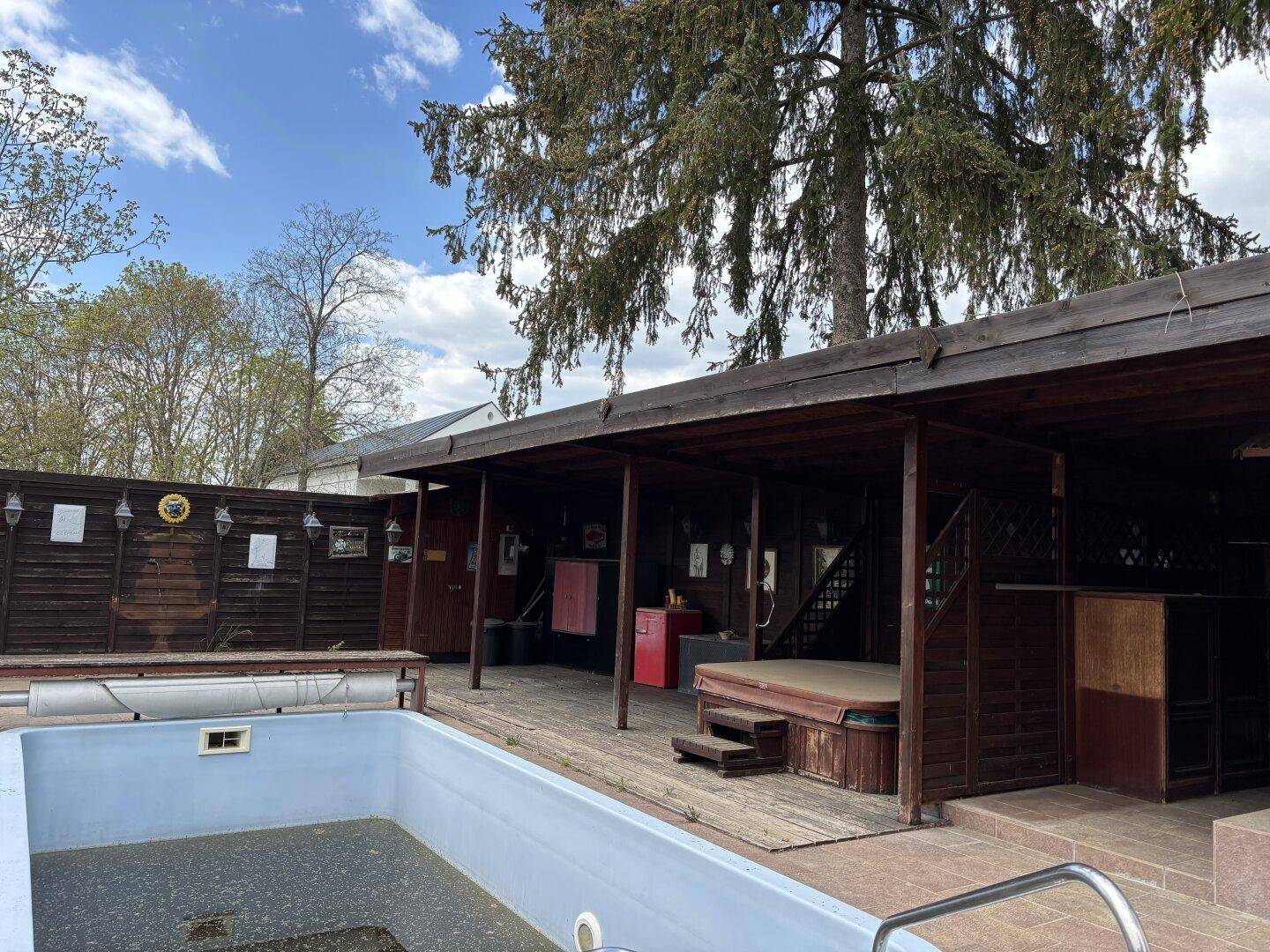 Außenbereich mit großem Pool und überdachtem Bereich, der einen Whirlpool und eine Bar umfasst.