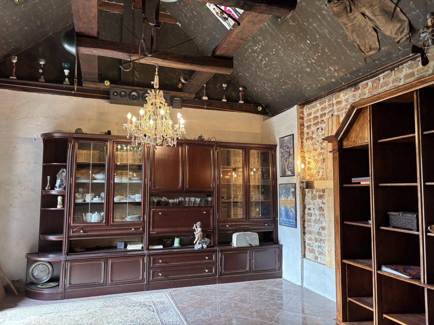 Geräumiger Wohnbereich mit einer großen Vitrine, einem opulenten Kronleuchter und rustikalen Elementen.