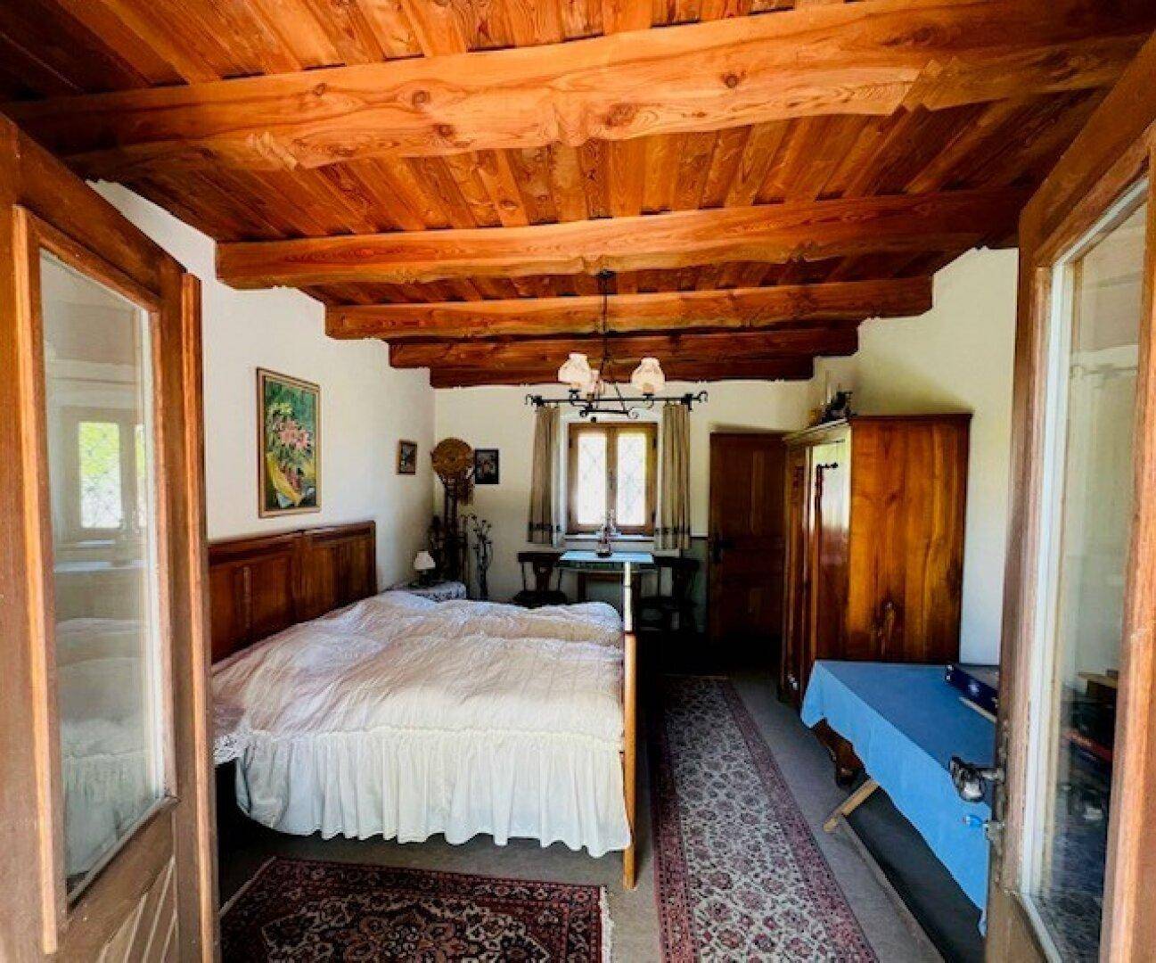 Gemütliches Schlafzimmer mit Holzbalkendecke, traditionellem Bett und rustikalem Mobiliar.