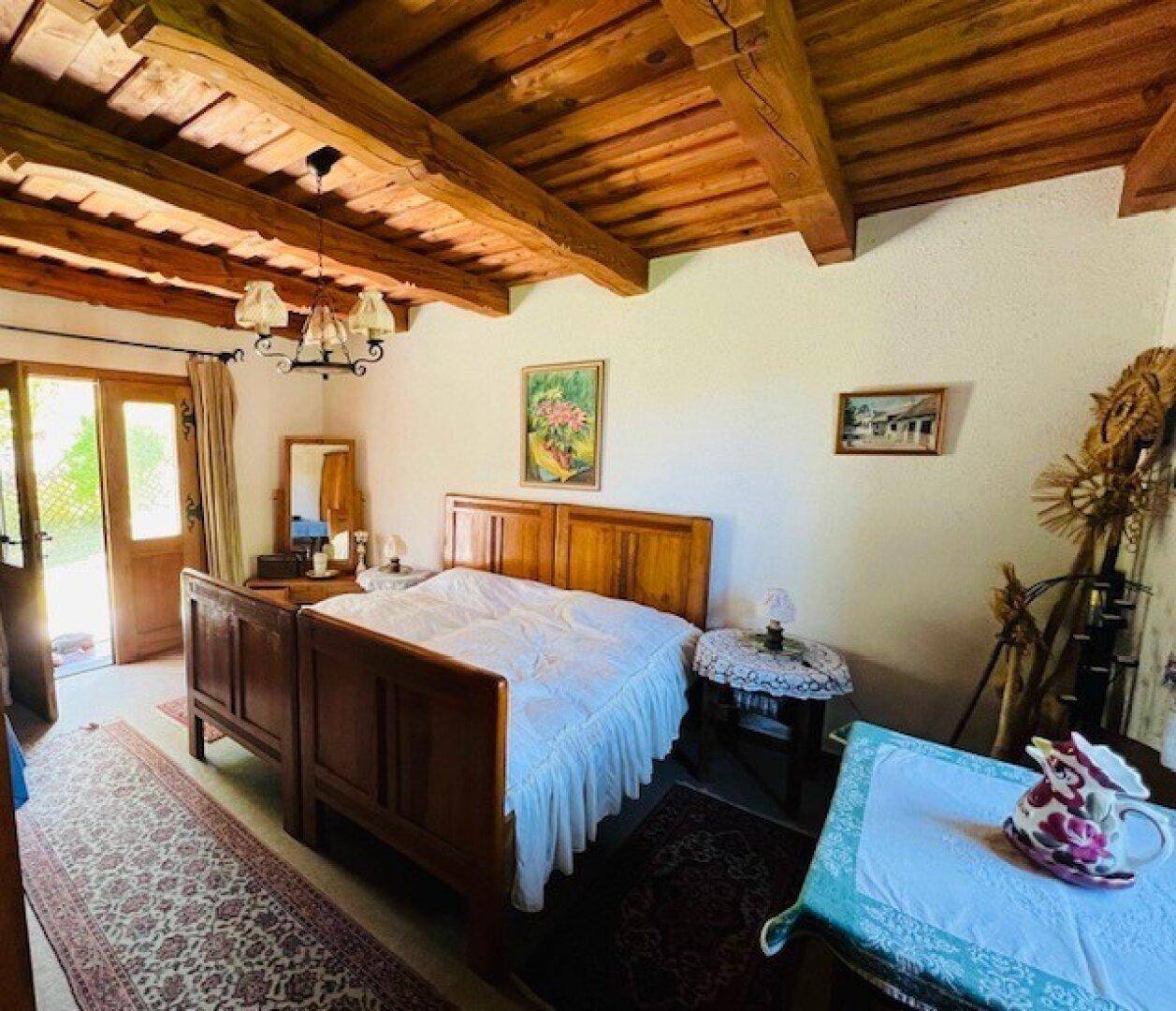 Helles Schlafzimmer mit Holzbalkendecke, traditionellem Bett und rustikalem Charme.