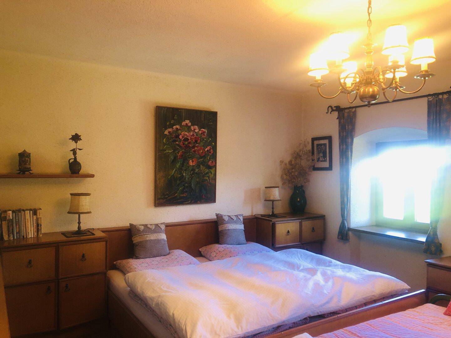 Schlafzimmer mit Doppelbett, traditionellen Holzmöbeln und einem Fenster.