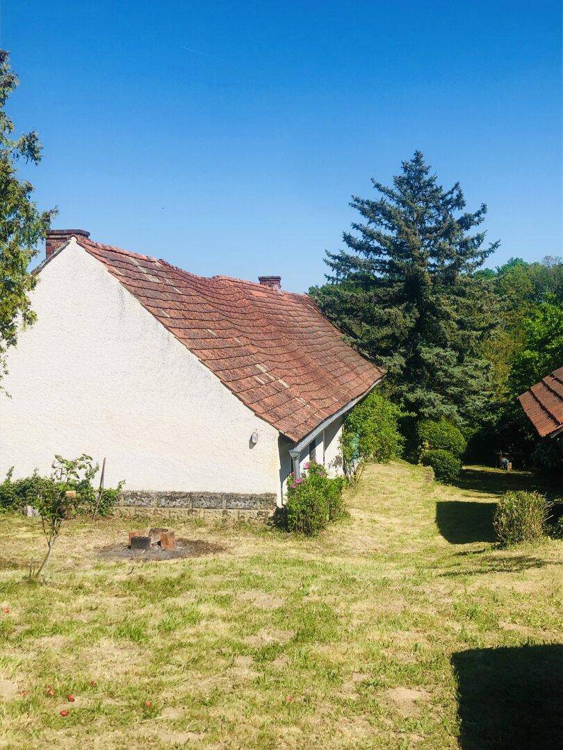 Seitenansicht des Hauses mit Ziegeldach und einem weitläufigen, sonnigen Gartenbereich.