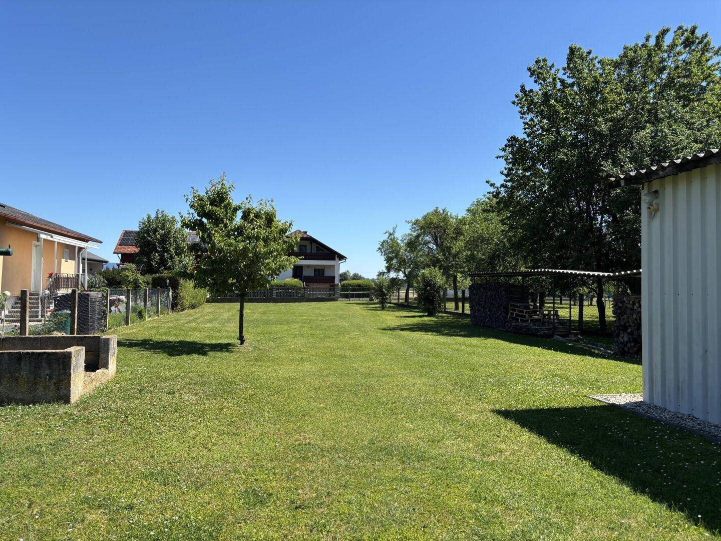 Großer, gepflegter Garten mit Rasenfläche und Bäumen, umgeben von ländlicher Umgebung.