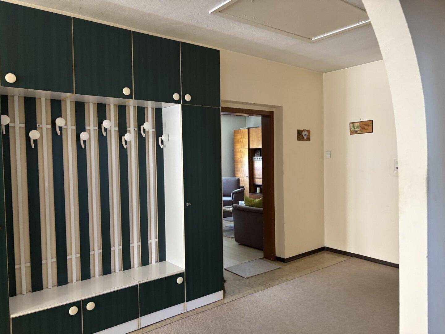 Flur mit einem eingebauten Garderobenschrank in Dunkelgrün und Weiß.