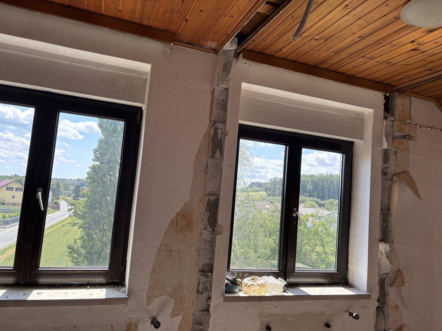 Fenster mit Blick auf die Straße, umliegende Häuser und die grüne Landschaft.