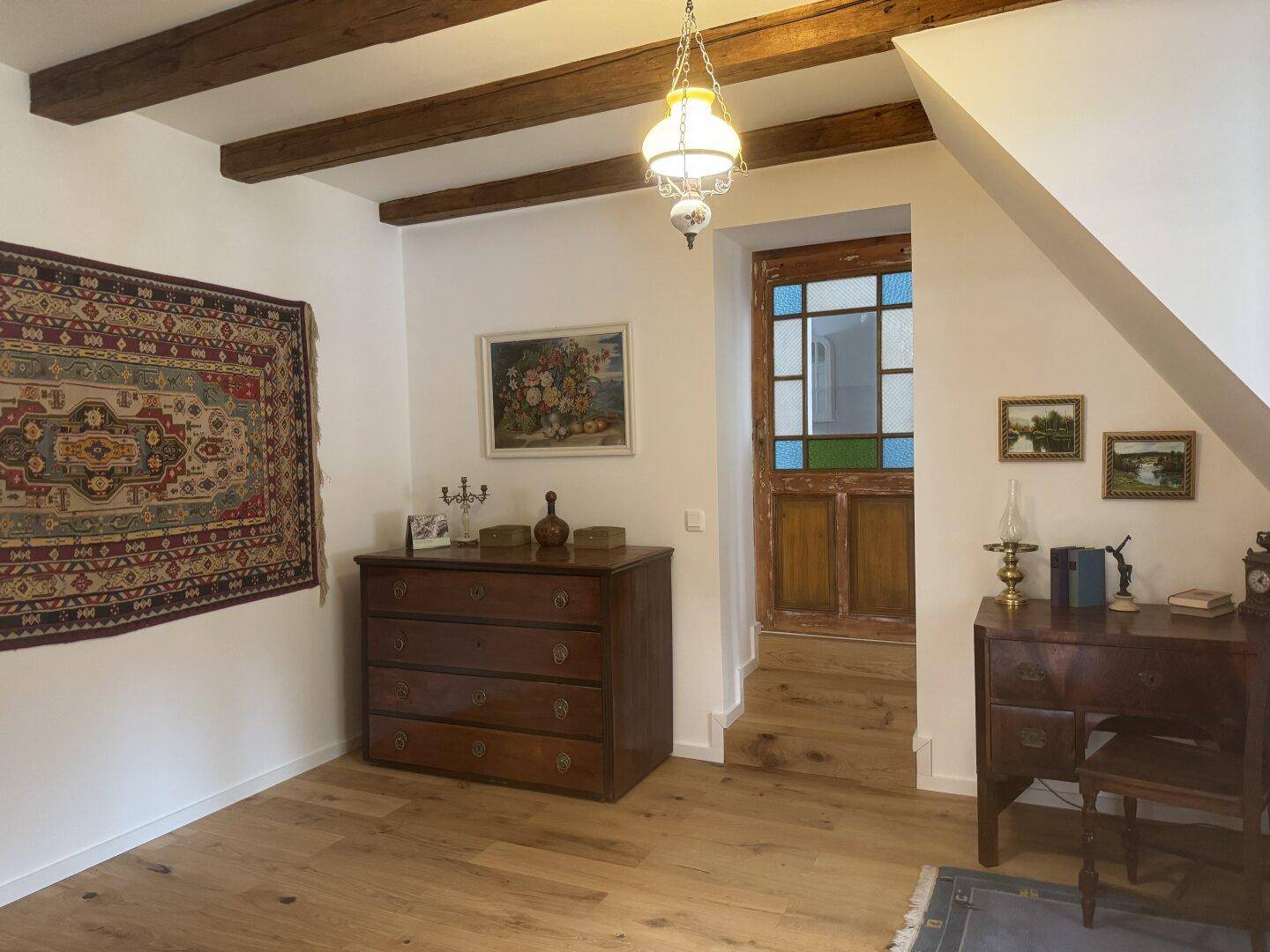 Geräumiger Flur im Obergeschoss mit Holzbalken, Holzboden und traditionellen Möbeln.